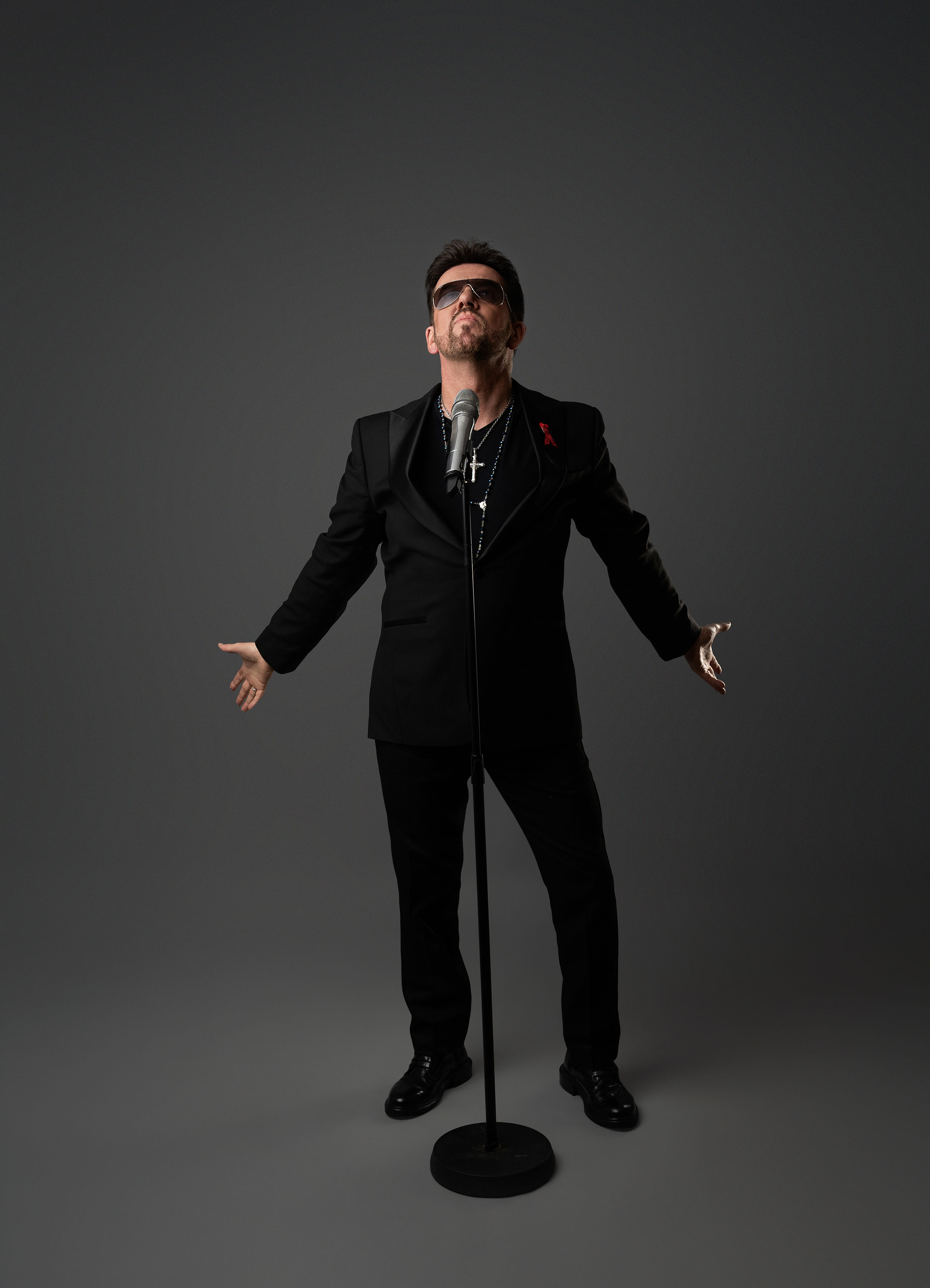 Steve Mitchell with arms wide open in dramatic pose against gray background