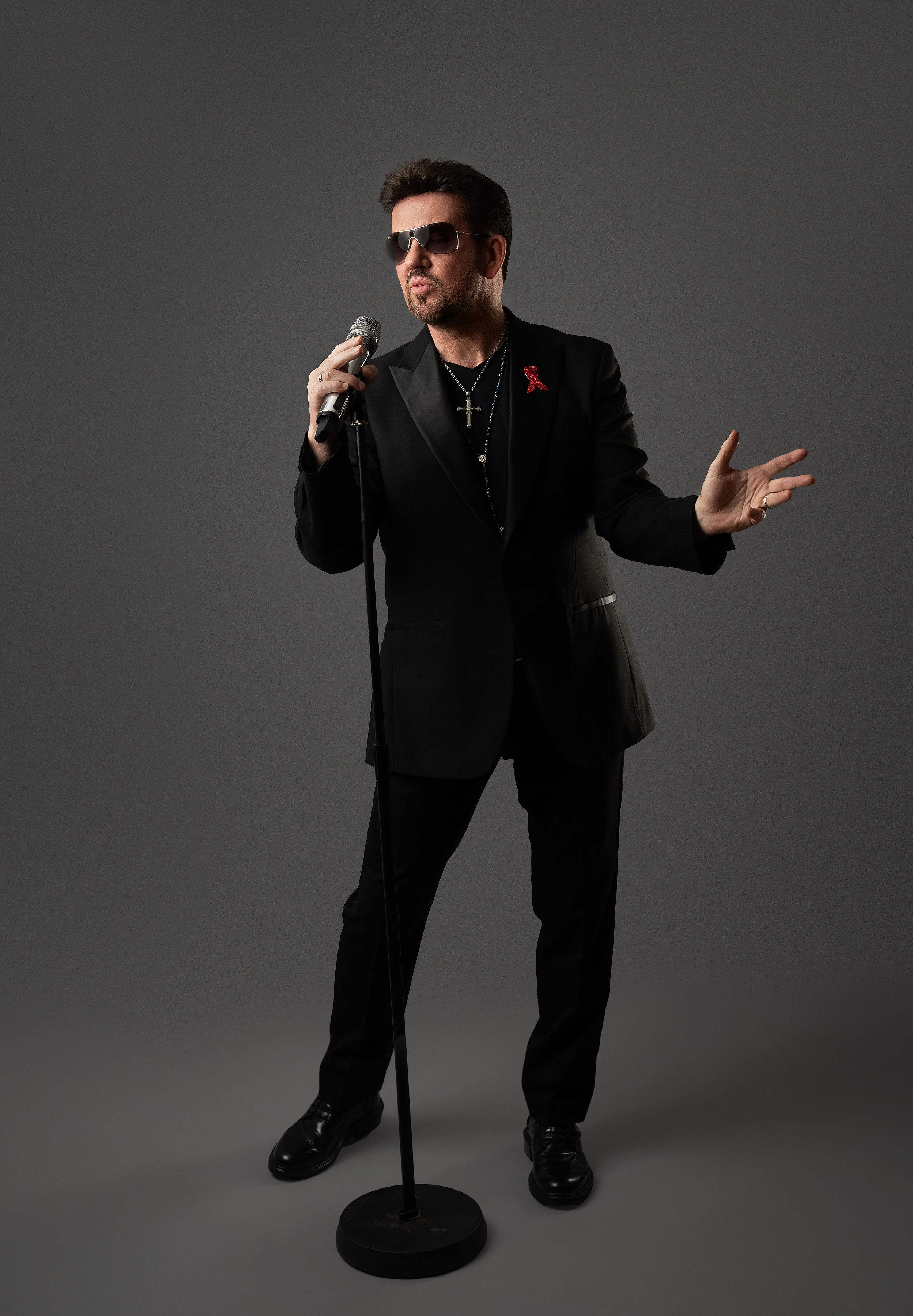 Full body shot of Steve Mitchell in black suit performing with microphone