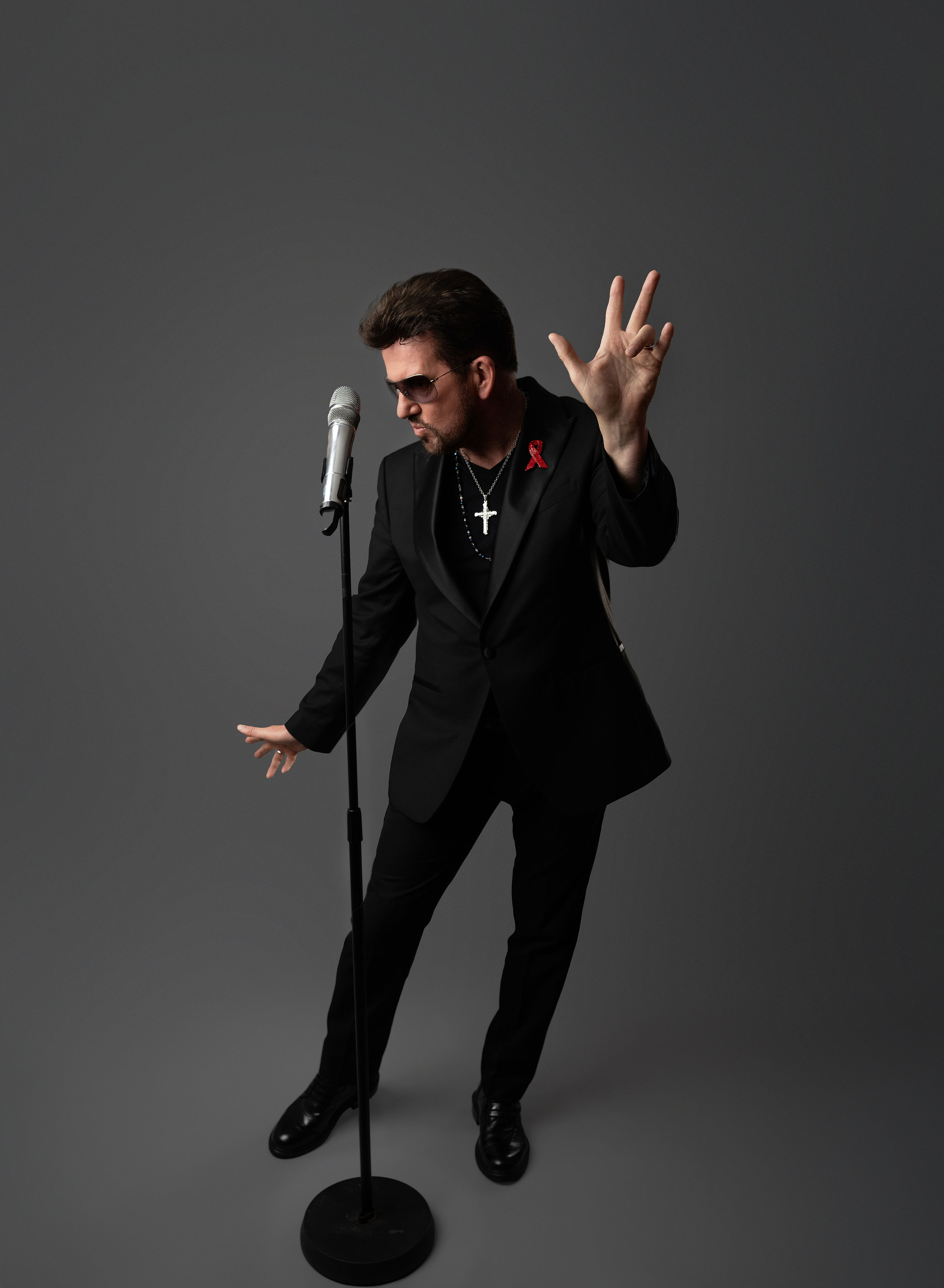 Steve Mitchell in dynamic dance pose with hand raised against gray background