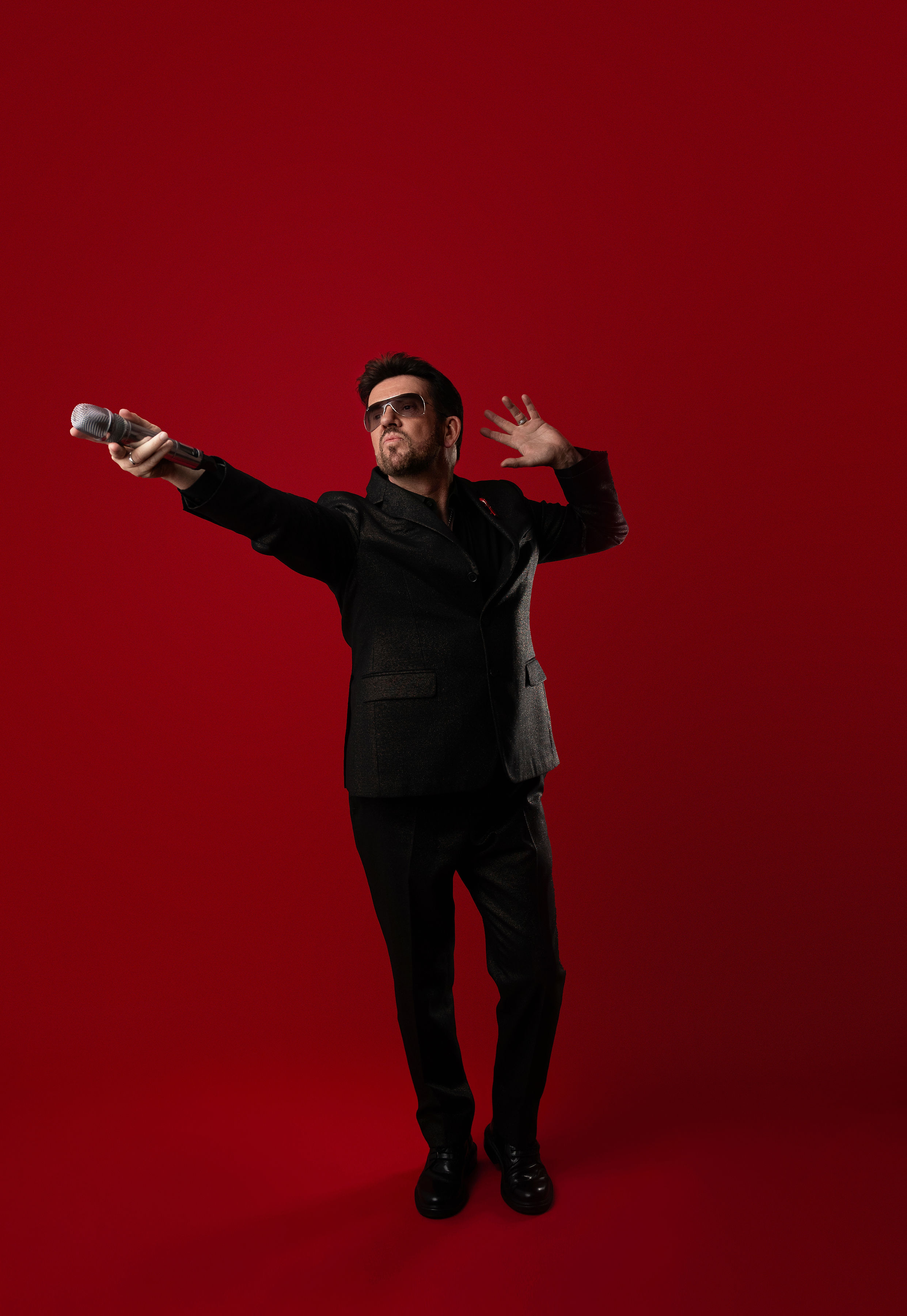 Steve Mitchell with arms spread wide extending microphone to audience