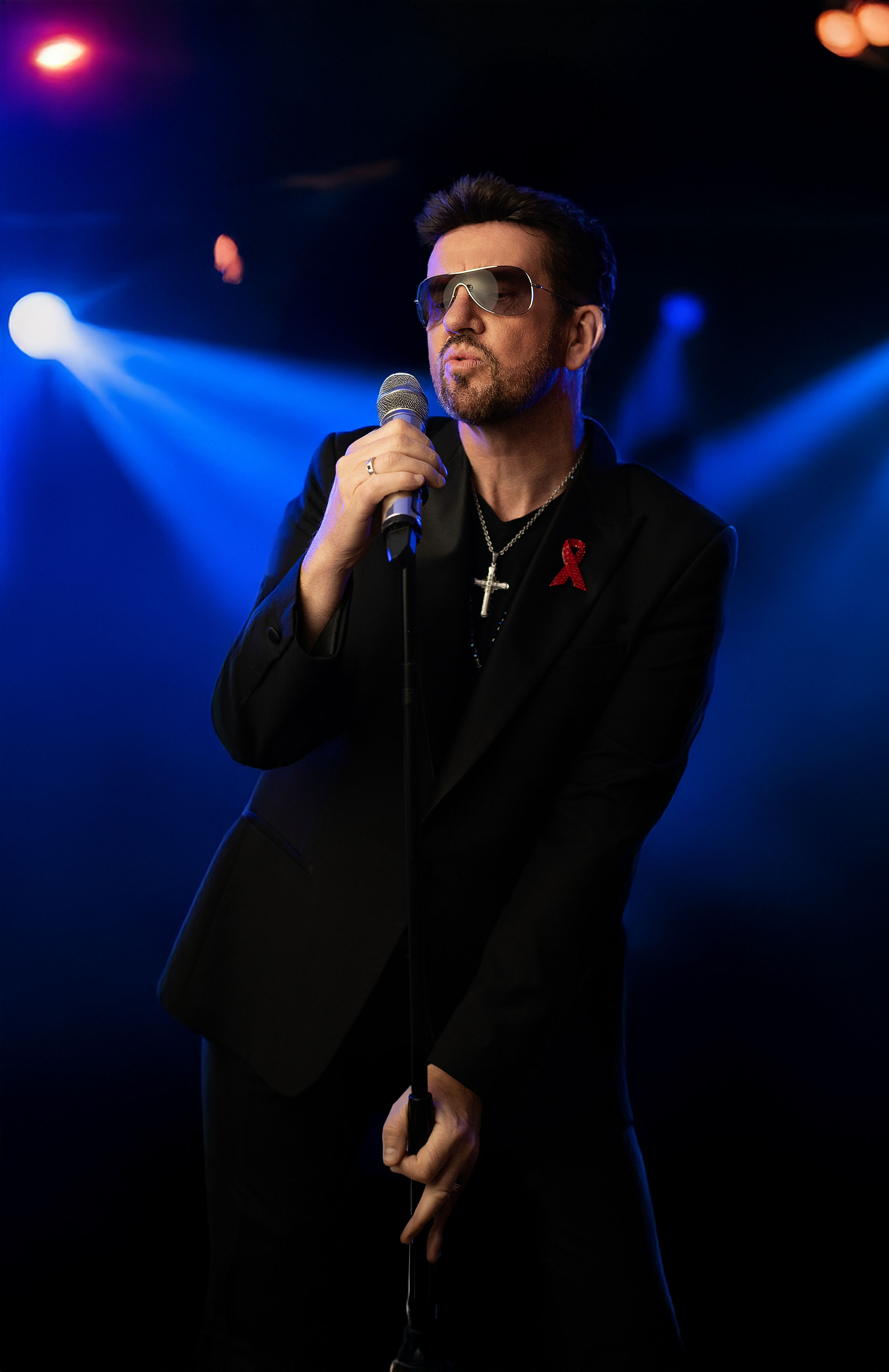 Steve Mitchell performing with microphone under blue stage lights