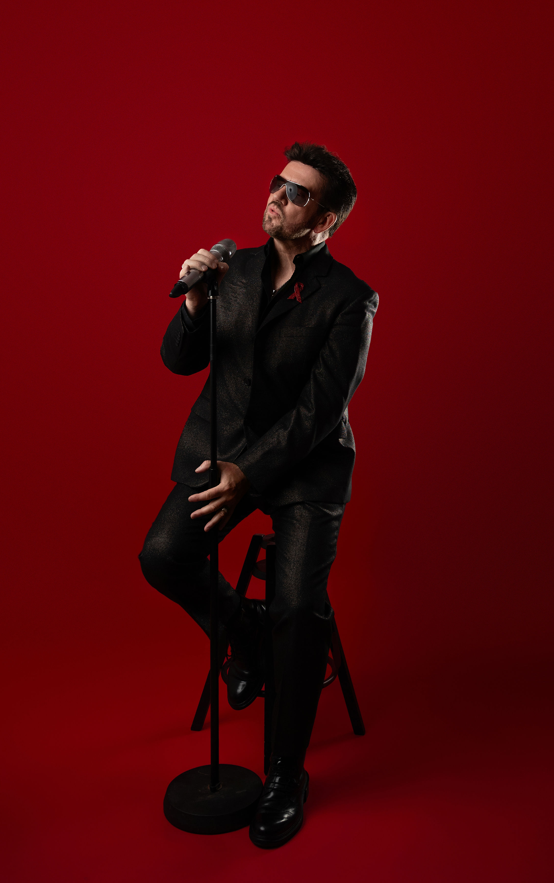 Steve Mitchell on stool looking upward while performing