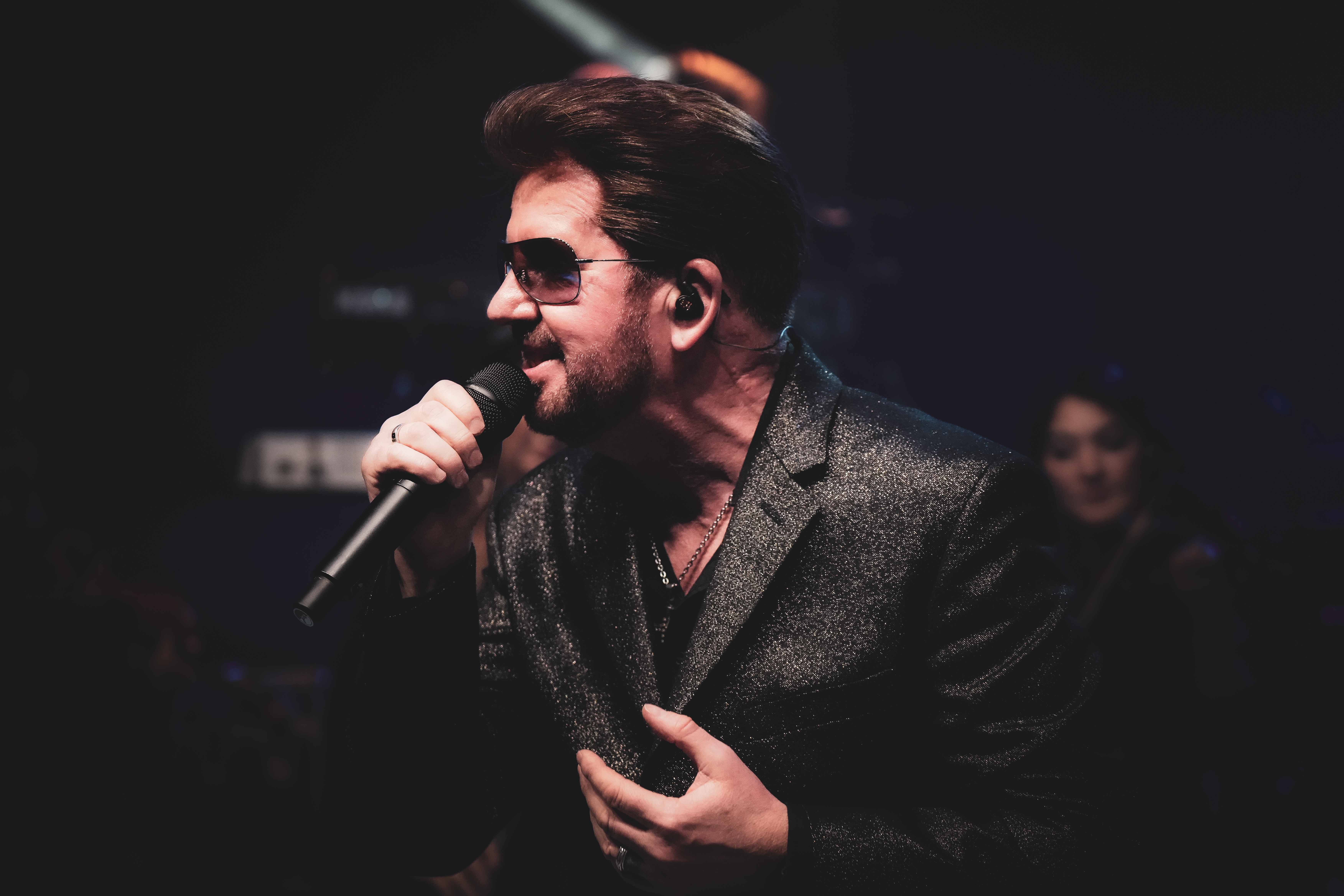 Close-up performance shot of Steve Mitchell with sunglasses in sparkly jacket