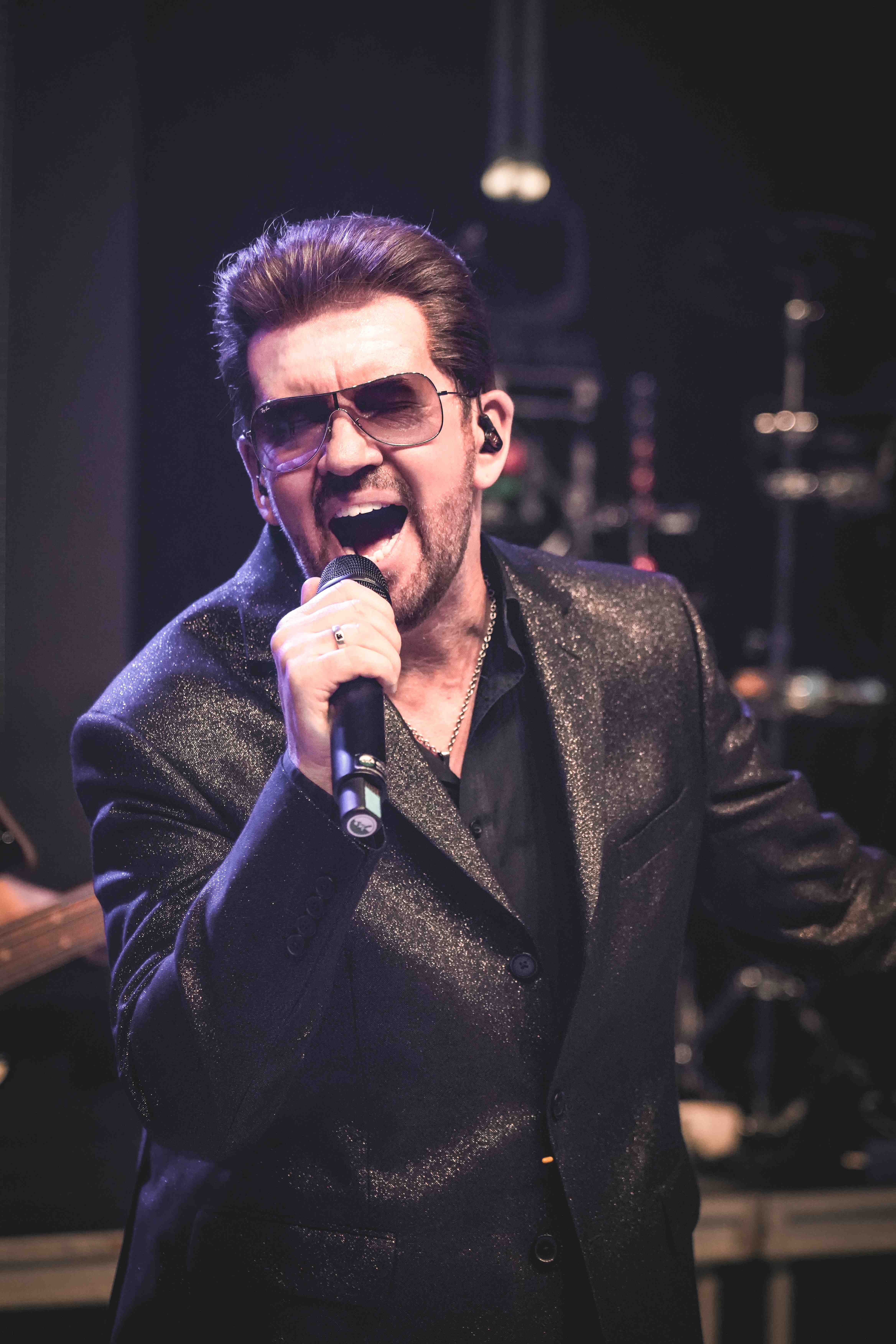 Dynamic shot of Steve Mitchell singing passionately with dramatic purple lighting